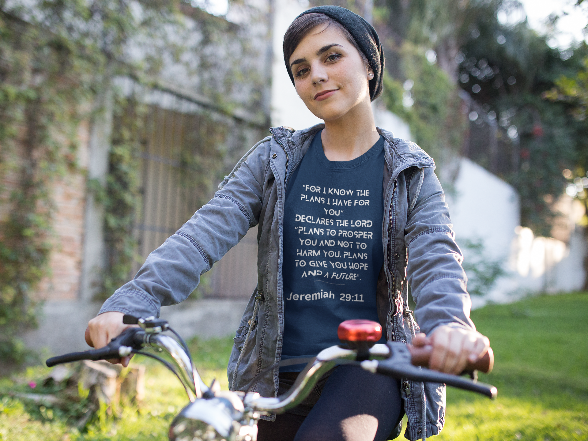 Person wearing a t-shirt with a biblical verse while riding a bicycle outdoors.