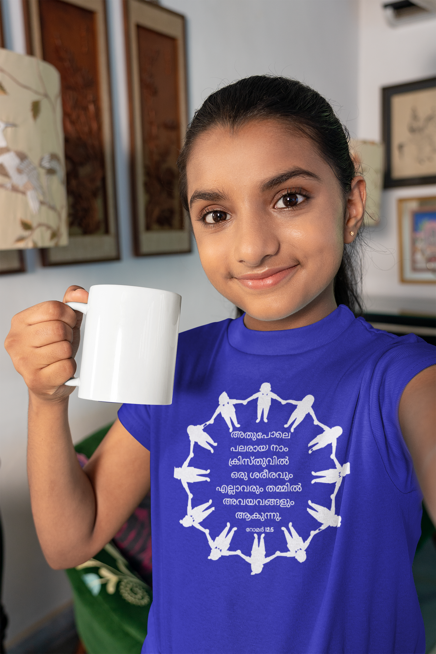Young girl wearing a blue sleeveless shirt with a white design, holding a white mug.