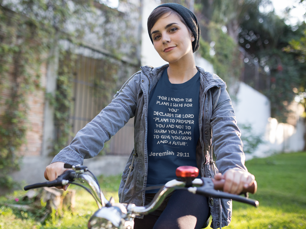 Person wearing a t-shirt with a biblical verse while riding a bicycle outdoors.
