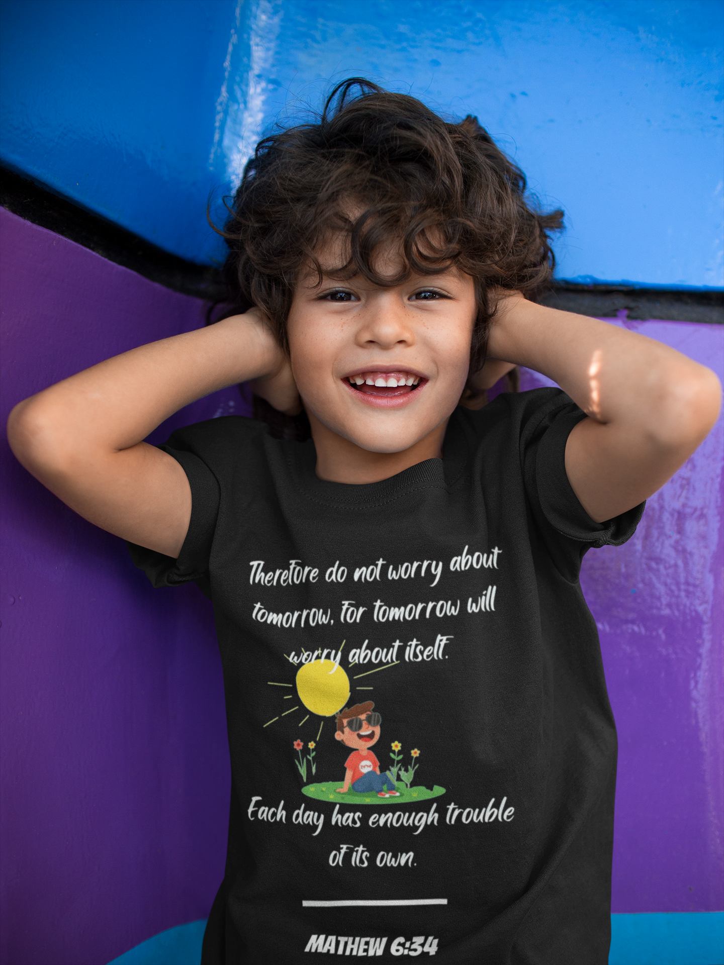 Child wearing a black t-shirt with a motivational quote and illustration, posing against a colorful background.