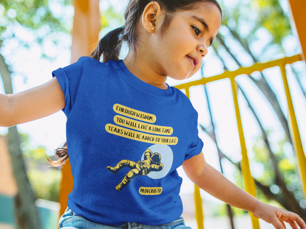 Child wearing a blue t-shirt with a design and text outdoors