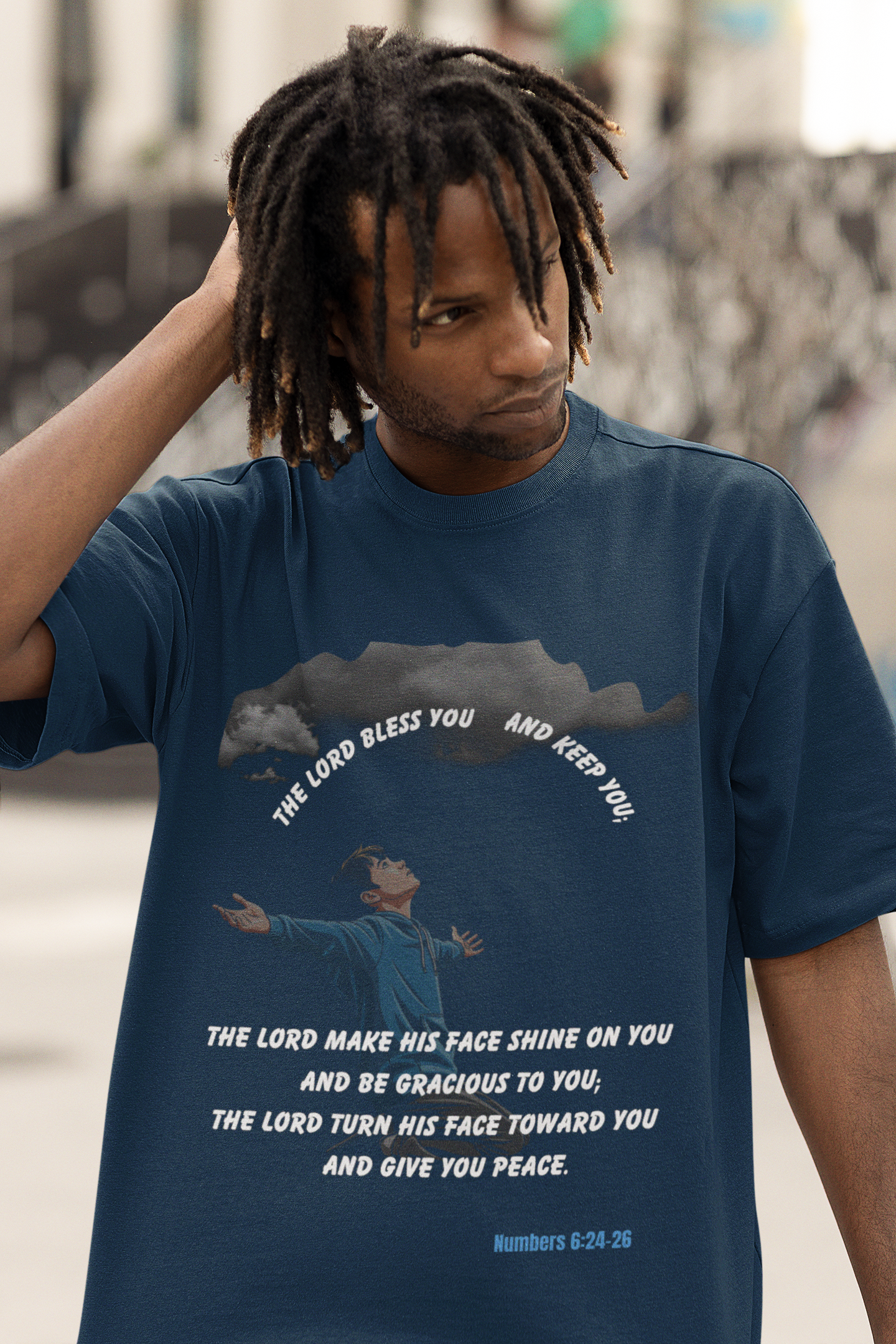 Person wearing a blue t-shirt with a graphic and text, standing outdoors.