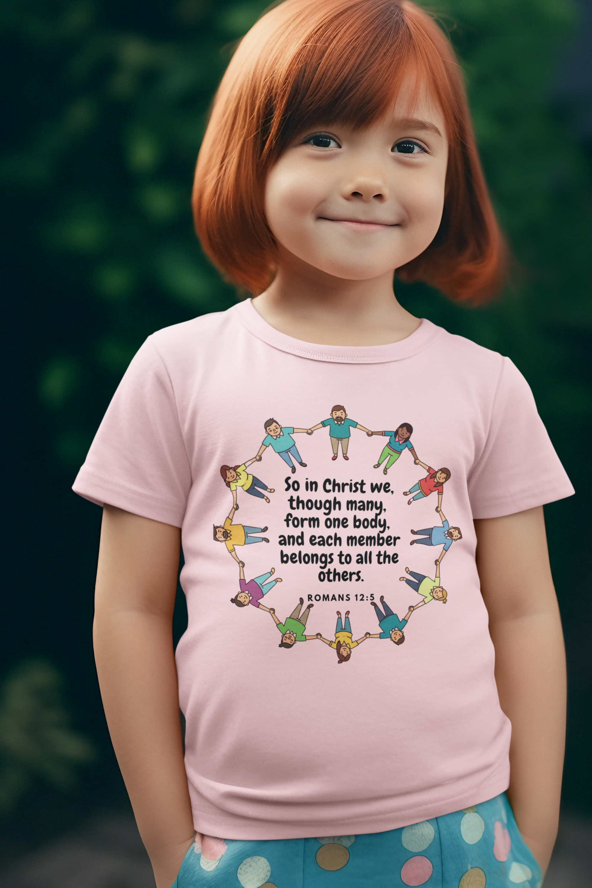 Child wearing a pink t-shirt with a colorful graphic and text, standing outdoors.