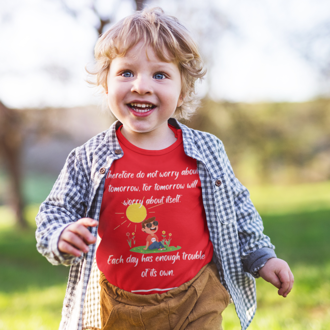 Child wearing a red shirt with text outdoors on a sunny day