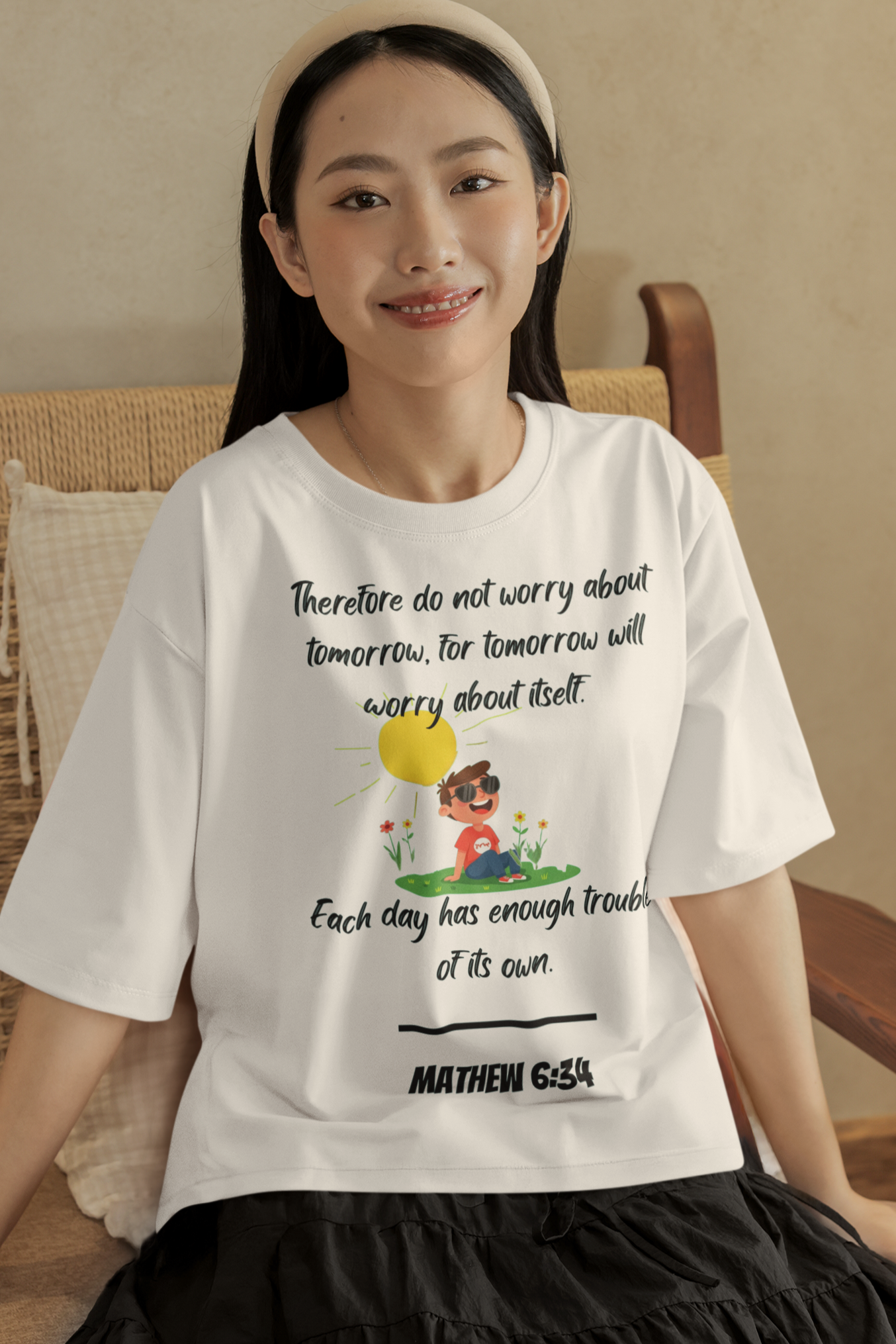 Woman wearing a white t-shirt with a graphic and text, sitting on a couch.