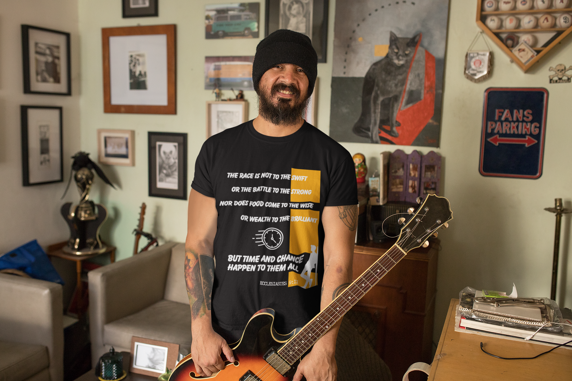 Man holding a guitar in a room with various decorations on the walls.