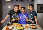 Three people wearing t-shirts with a design, standing around a table with food items.