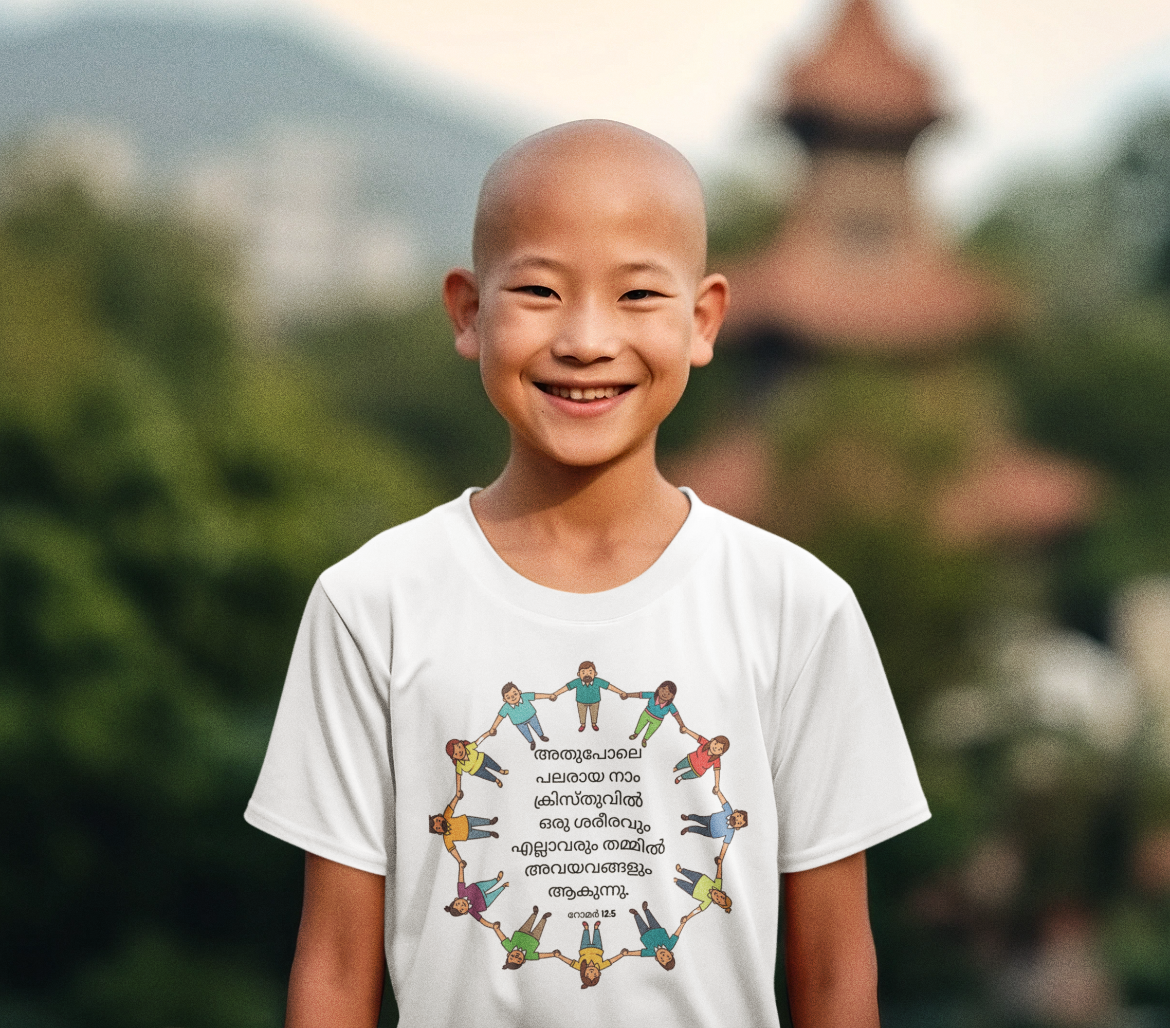 Child wearing a white t-shirt with a colorful design and text, standing outdoors with greenery in the background.