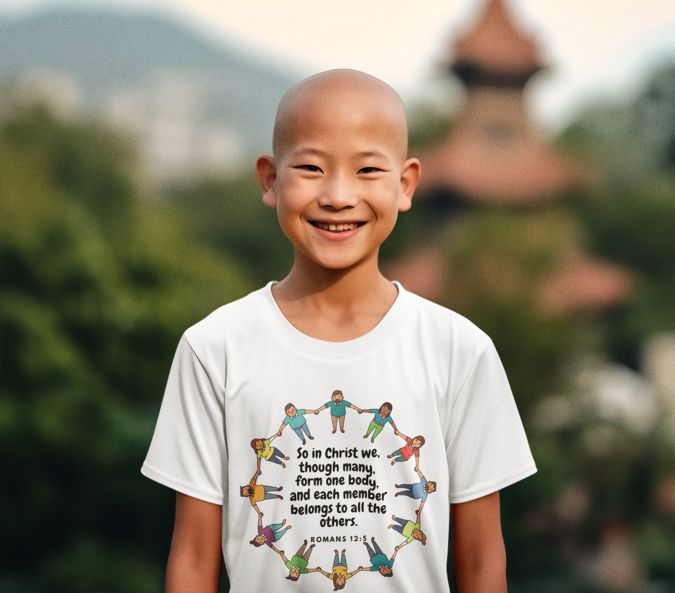 Child wearing a white t-shirt with a colorful design and text, standing outdoors with greenery in the background.