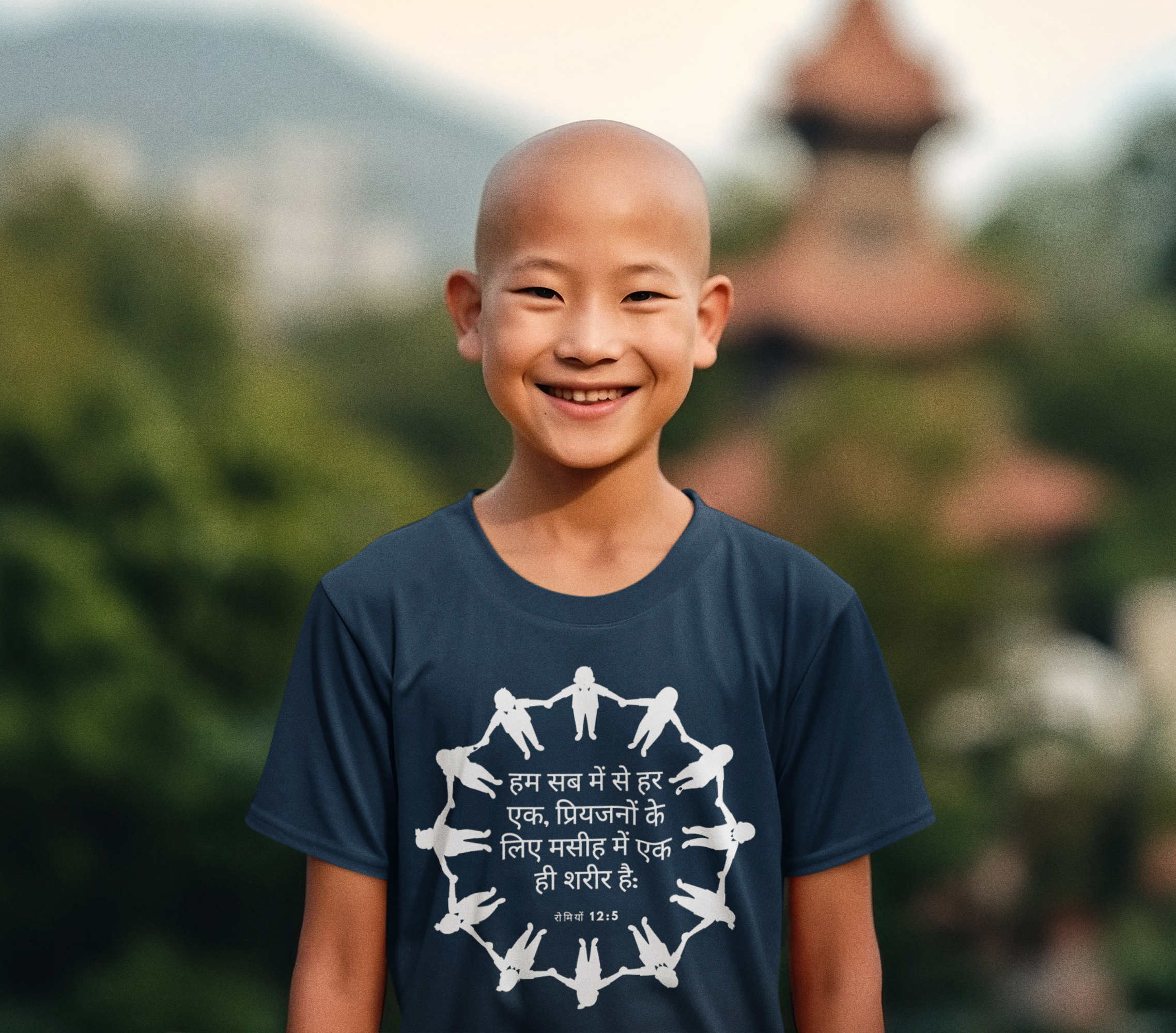 Child wearing a navy blue t-shirt with white graphics and text, standing outdoors with greenery in the background.