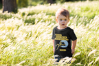 Child wearing a black t-shirt with Bible Verse and graphics in a grassy field