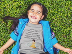 Child lying on grass wearing a blue jacket and gray shirt with text
