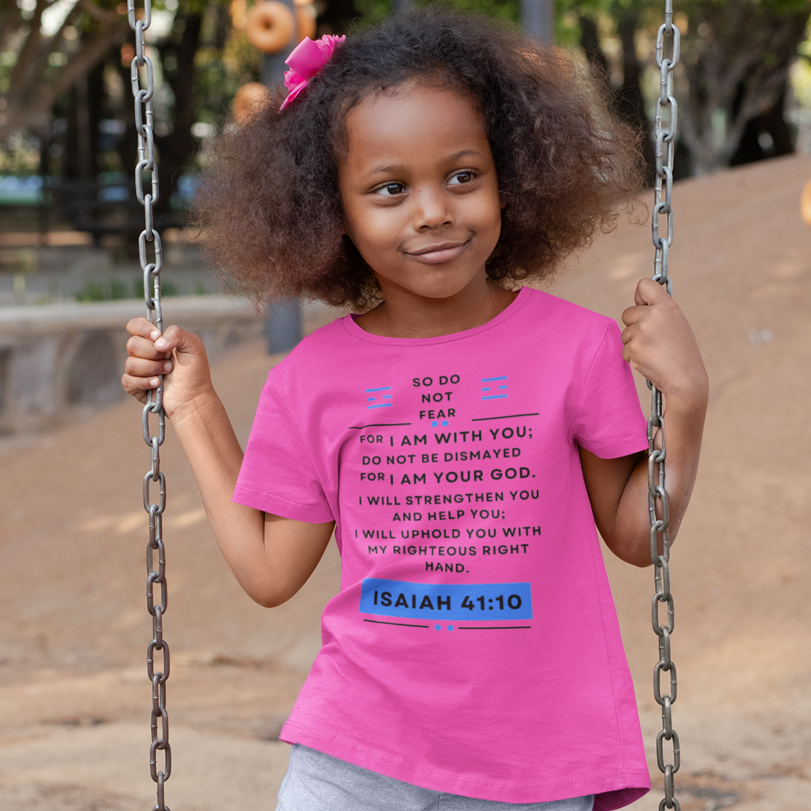 Child in pink shirt and gray pants on a swing at a playground