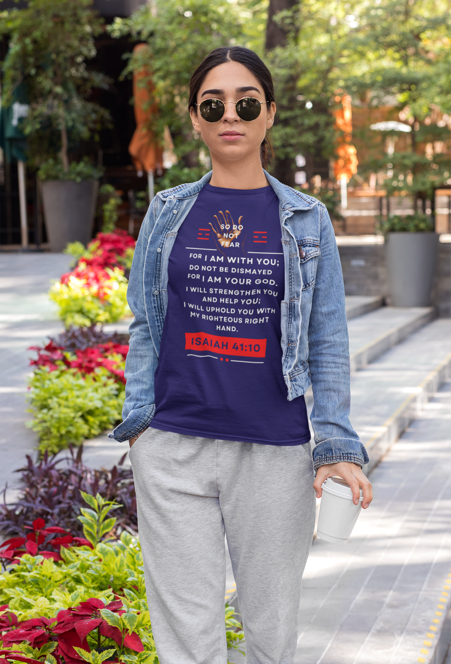 Person wearing a blue t-shirt with text, denim jacket, and gray pants in an outdoor setting.