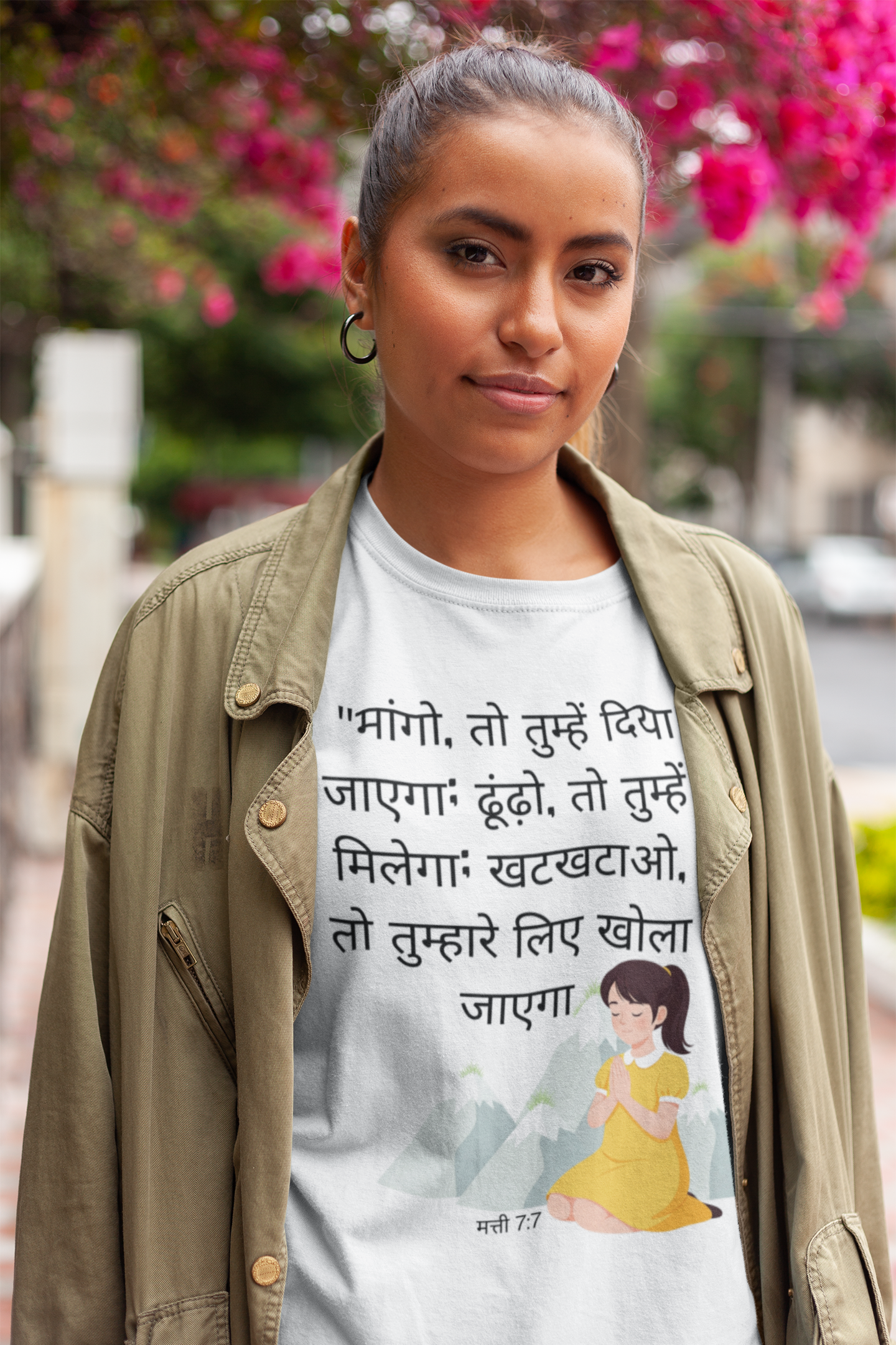 Person wearing a t-shirt with text and a graphic, standing outdoors with blurred background