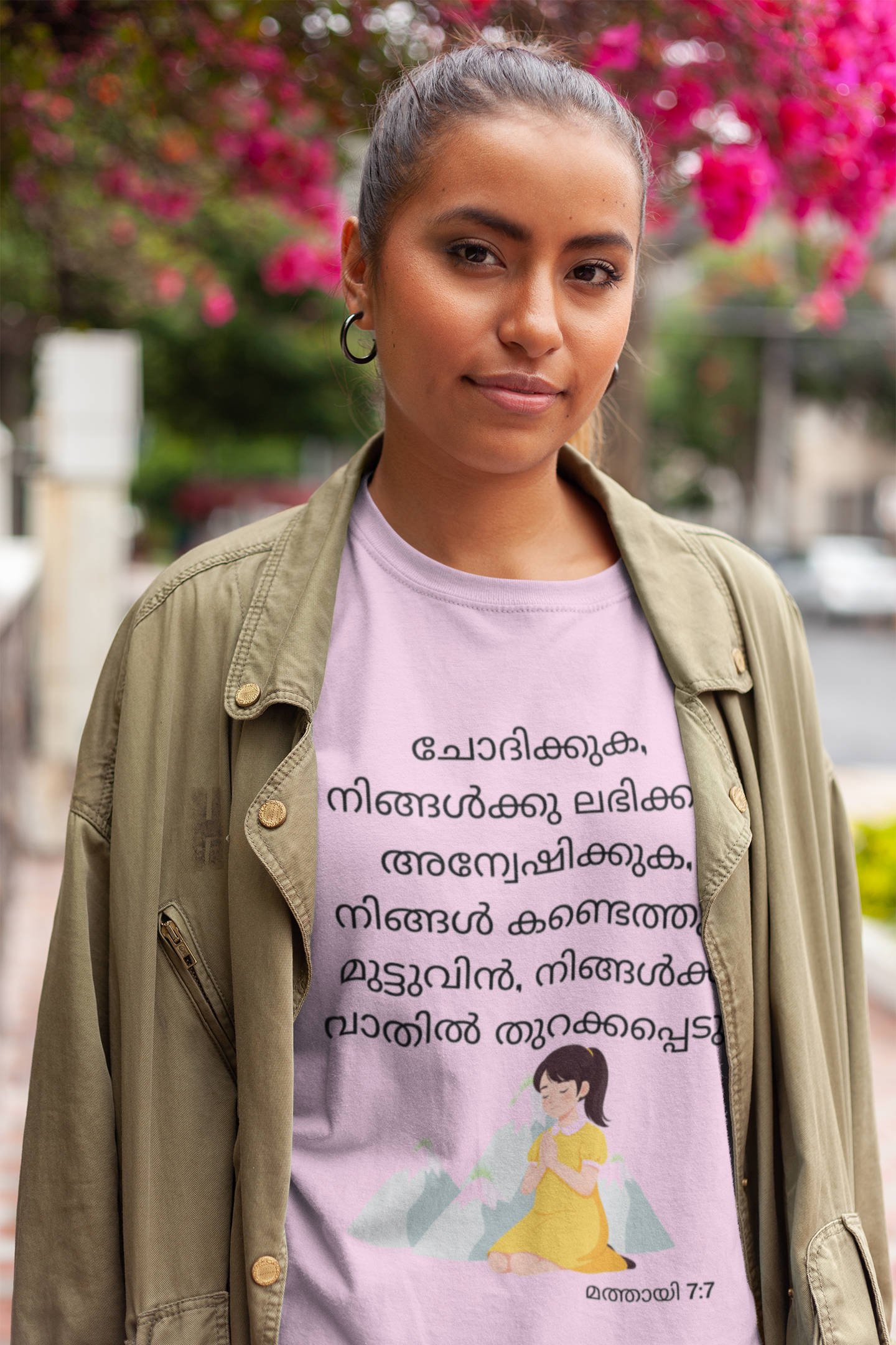 Person wearing a purple t-shirt with text and graphics, standing outdoors with blurred background